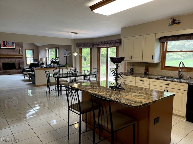 12701 Gordon St, North Royalton, OH 44133 - kitchen with a brick fireplace, white cabinets, decorative backsplash, a breakfast bar area, and dark stone counters