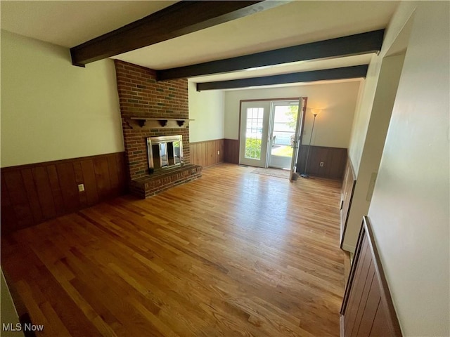 180 Atterbury Blvd, Hudson, OH 44236 - unfurnished living room featuring wainscoting, wood finished floors, beam ceiling, wood walls, and a brick fireplace