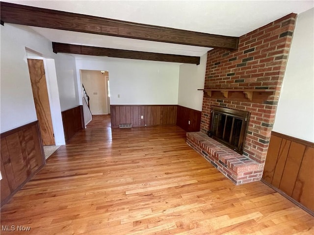 180 Atterbury Blvd, Hudson, OH 44236 - unfurnished living room with a wainscoted wall, wood walls, light wood-type flooring, beam ceiling, and a brick fireplace