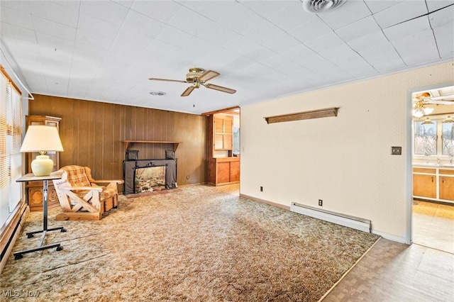 12873 Unity Rd, New Springfield, OH 44443 - living room featuring baseboard heating, wood walls, a ceiling fan, and a fireplace with flush hearth