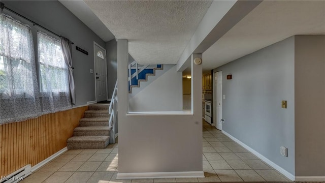 62253 Forestview Dr, Cambridge, OH 43725 - stairs featuring tile patterned flooring, a textured ceiling, wooden walls, baseboard heating, and baseboards