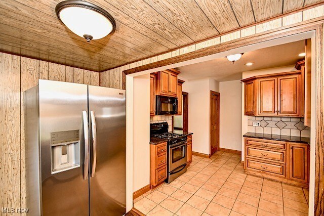 837 Lake Ave NE, Massillon, OH 44646 - kitchen featuring stainless steel appliances, backsplash, light tile patterned floors, brown cabinetry, and wooden ceiling