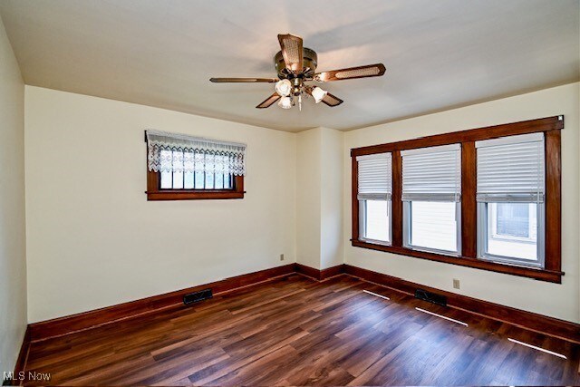 837 Lake Ave NE, Massillon, OH 44646 - unfurnished room featuring baseboards, dark wood-style floors, and a ceiling fan