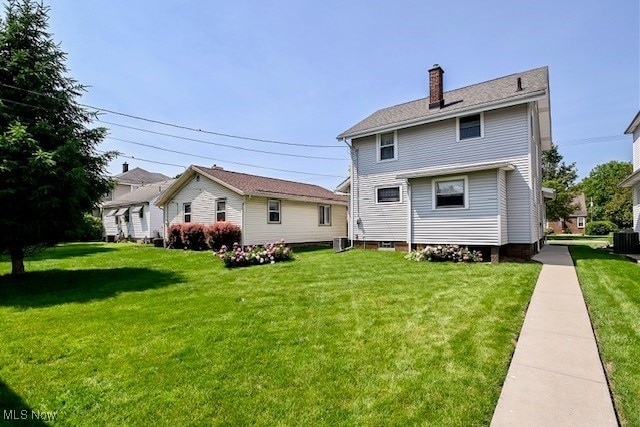 837 Lake Ave NE, Massillon, OH 44646 - rear view of house with a yard, a chimney, and cooling unit