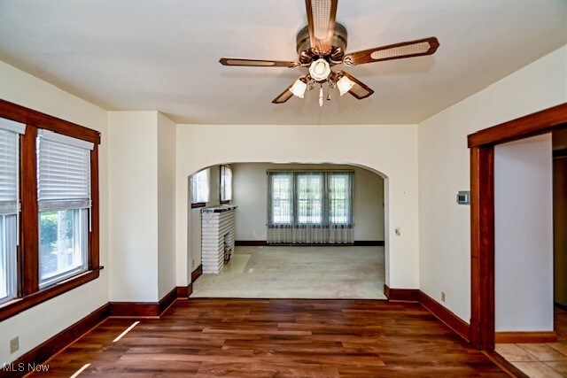 837 Lake Ave NE, Massillon, OH 44646 - unfurnished room with arched walkways, a ceiling fan, baseboards, and wood finished floors