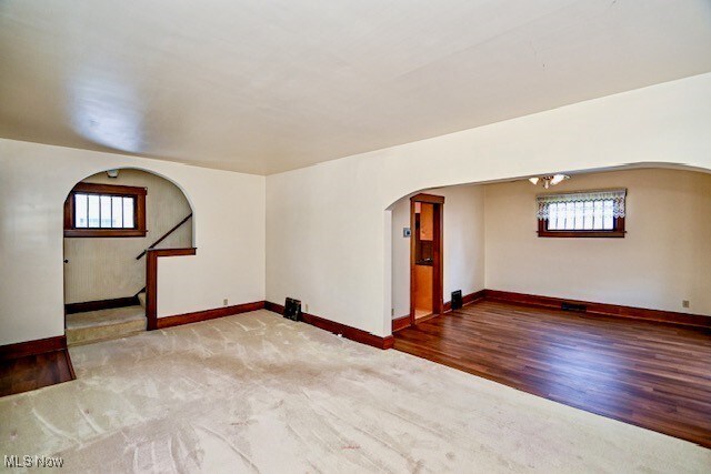 837 Lake Ave NE, Massillon, OH 44646 - spare room with arched walkways, healthy amount of natural light, baseboards, and wood finished floors