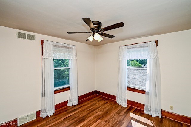837 Lake Ave NE, Massillon, OH 44646 - unfurnished room featuring plenty of natural light, baseboards, dark wood-style floors, and a ceiling fan