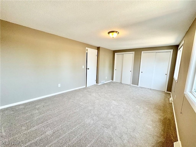 6400 Center St Unit 14, Mentor, OH 44060 - unfurnished bedroom with multiple closets, light carpet, a textured ceiling, and baseboards
