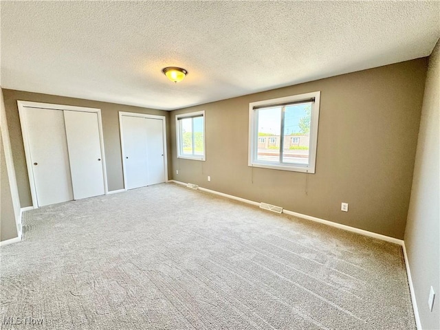 6400 Center St Unit 14, Mentor, OH 44060 - unfurnished bedroom with two closets, a textured ceiling, carpet flooring, and baseboards