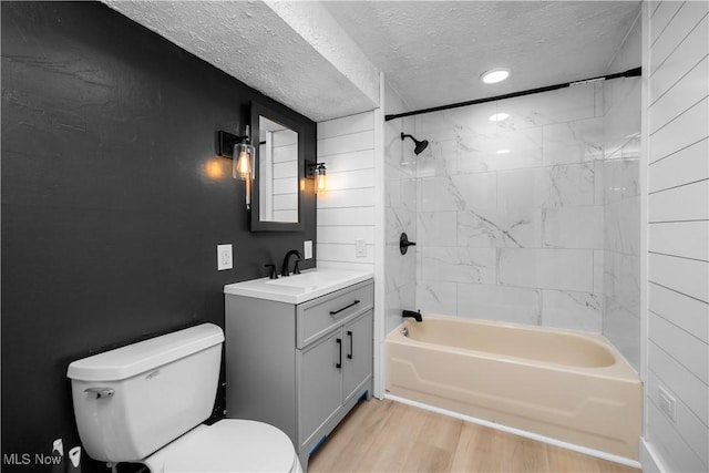 348 Elberta Dr, Vermilion, OH 44089 - bathroom with a textured ceiling, toilet, wood finished floors, vanity, and  shower combination