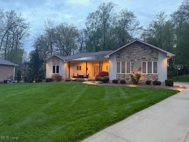 4340 Castlegate Blvd, Uniontown, OH 44685 - view of front facade featuring stone siding, a front lawn, a standing seam roof, and metal roof