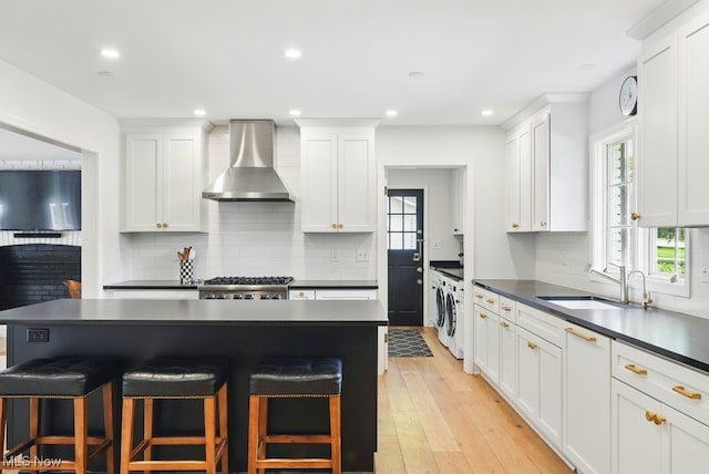 19 Brandywood Dr, Pepper Pike, OH 44124 - kitchen featuring wall chimney range hood, dark countertops, a kitchen bar, healthy amount of natural light, and recessed lighting