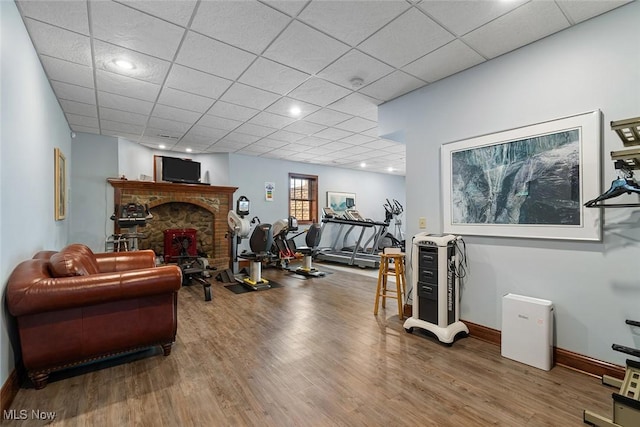 5495 Meese Rd NE, Louisville, OH 44641 - workout area featuring wood finished floors, baseboards, a fireplace, and a paneled ceiling
