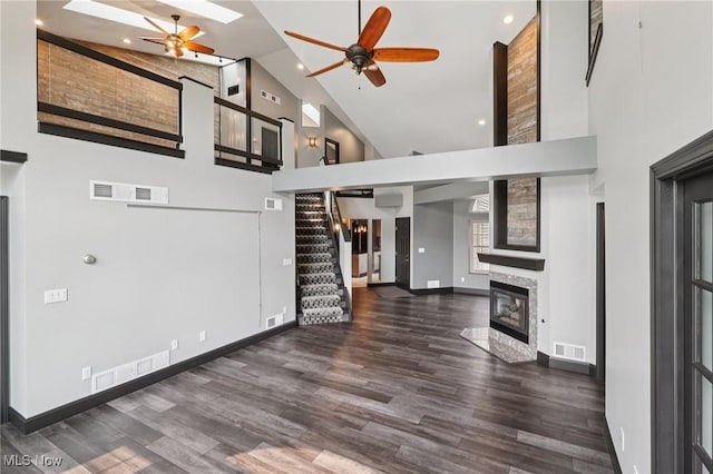 322 N Bayshore Dr Unit 3, Columbiana, OH 44408 - unfurnished living room with high vaulted ceiling, ceiling fan, stairway, a fireplace with flush hearth, and wood finished floors