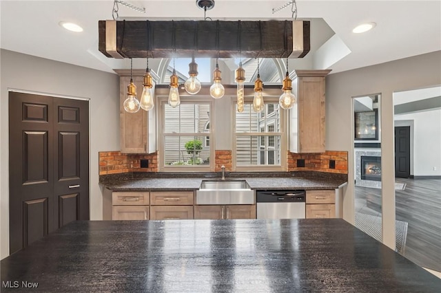 322 N Bayshore Dr Unit 3, Columbiana, OH 44408 - kitchen featuring stainless steel dishwasher, a sink, dark countertops, tasteful backsplash, and a glass covered fireplace