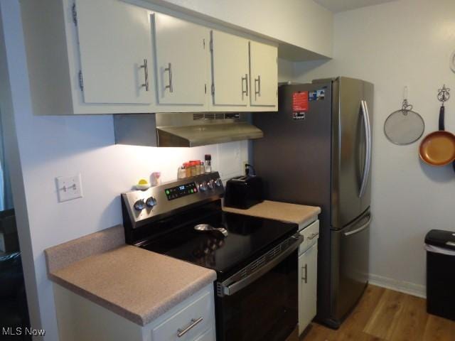 16395 Heather Ln Unit 201, Middleburg Heights, OH 44130 - kitchen with black electric range, under cabinet range hood, wood finished floors, white cabinets, and baseboards