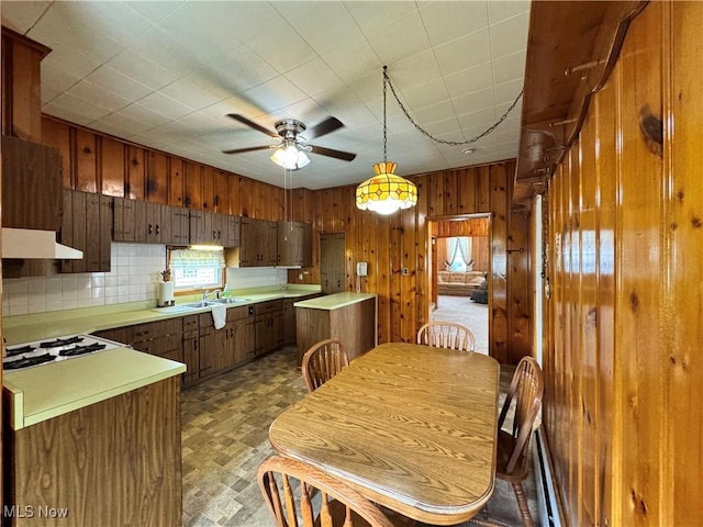 99 W Martin St, East Palestine, OH 44413 - kitchen featuring white cooktop, light countertops, wood walls, a sink, and a ceiling fan