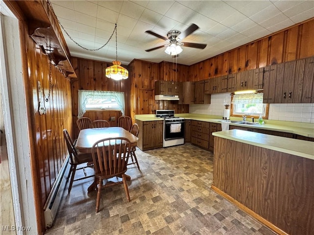 99 W Martin St, East Palestine, OH 44413 - kitchen featuring gas range gas stove, under cabinet range hood, wood walls, light countertops, and a sink