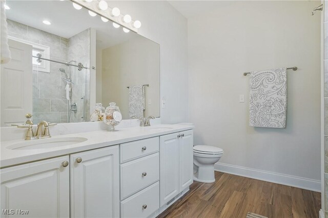 1983 Fox Trace Trl, Cuyahoga Falls, OH 44223 - bathroom featuring double vanity, toilet, tiled shower, wood finished floors, and baseboards