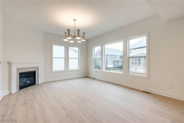 S/L12 Neptune Oval, Solon, OH 44139 - unfurnished living room with a chandelier, light wood-type flooring, baseboards, and a glass covered fireplace