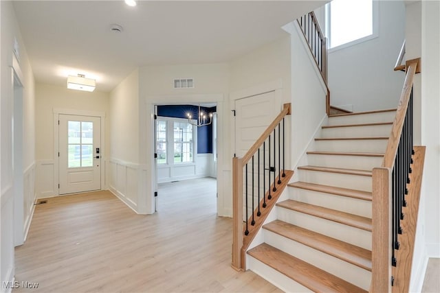 S/L12 Neptune Oval, Solon, OH 44139 - entryway featuring light wood-style floors, stairway, wainscoting, a chandelier, and a decorative wall