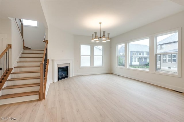 S/L12 Neptune Oval, Solon, OH 44139 - unfurnished living room featuring a chandelier, wood finished floors, stairway, baseboards, and a glass covered fireplace