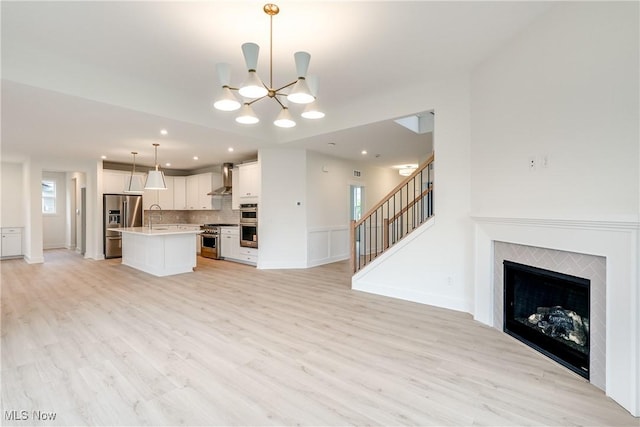 S/L12 Neptune Oval, Solon, OH 44139 - unfurnished living room with a sink, light wood-style flooring, a chandelier, stairs, and recessed lighting