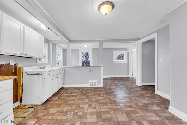 4611 W 41st St, Cleveland, OH 44109 - kitchen featuring baseboards, light countertops, brick patterned flooring, and white cabinets