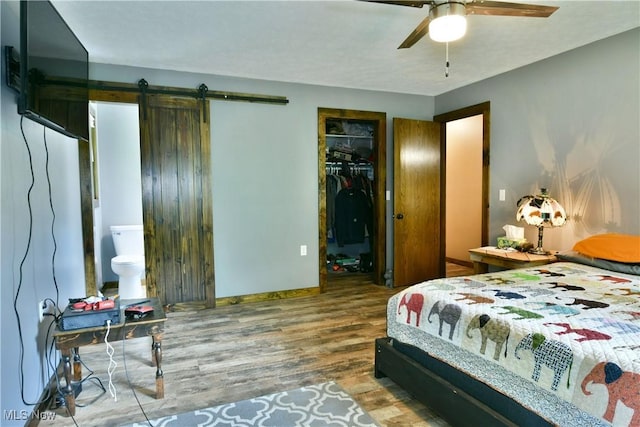 6416 Wilson Sharpsville Rd, Fowler, OH 44418 - bedroom with wood finished floors, a barn door, a spacious closet, a closet, and a ceiling fan