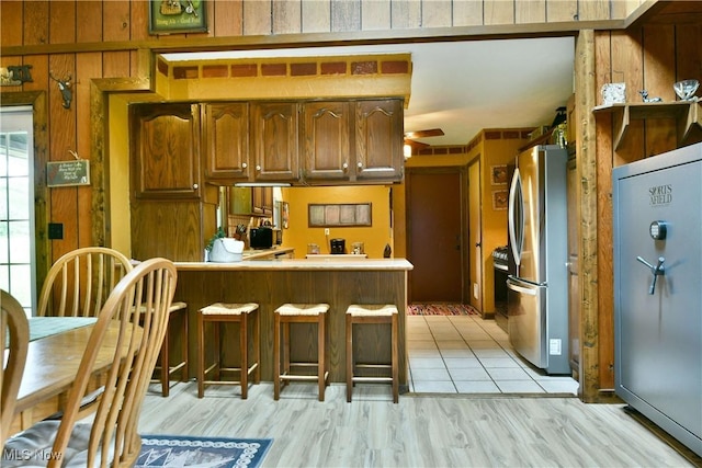 6416 Wilson Sharpsville Rd, Fowler, OH 44418 - kitchen featuring freestanding refrigerator, high end fridge, a peninsula, light wood-style flooring, and brown cabinetry