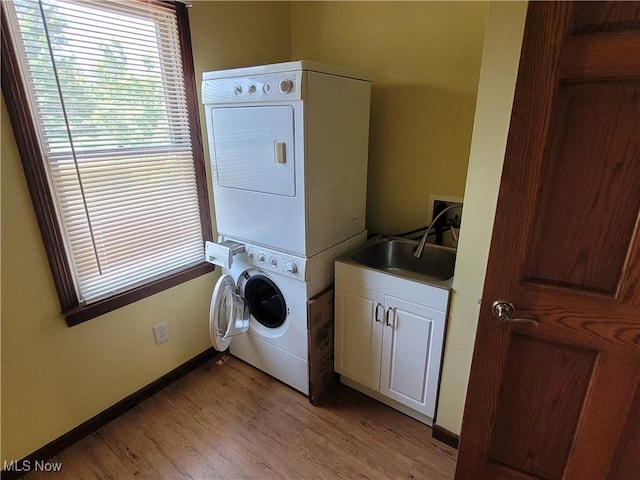 3172 Kinata Ct, West Salem, OH 44287 - laundry room featuring stacked washer and clothes dryer, cabinet space, light wood-type flooring, and baseboards