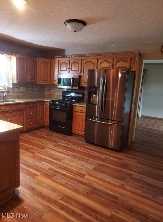 130 Maze Rd, Belpre, OH 45714 - kitchen with appliances with stainless steel finishes, wood finished floors, light countertops, a textured ceiling, and tasteful backsplash