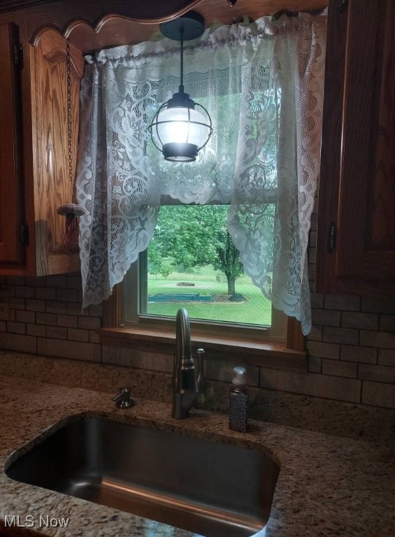 130 Maze Rd, Belpre, OH 45714 - kitchen view of decorative backsplash, hanging light fixtures, light stone countertops, and brown cabinetry