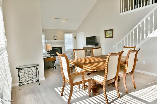 100 Turnberry Ct NE, Warren, OH 44484 - dining area with high vaulted ceiling, wood finished floors, a glass covered fireplace, baseboards, and stairs