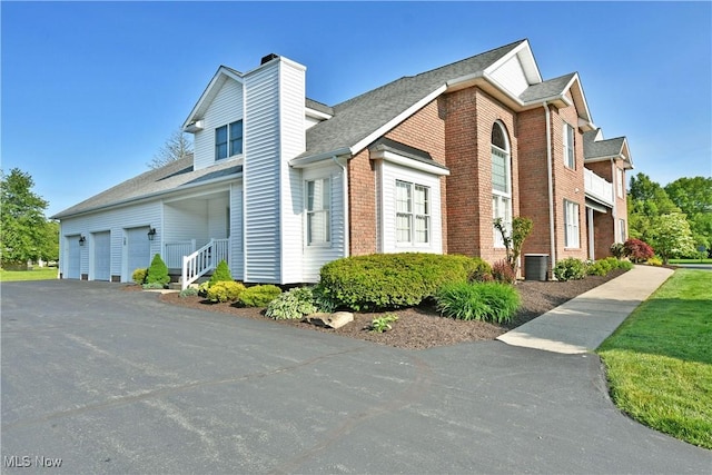 100 Turnberry Ct NE, Warren, OH 44484 - view of home's exterior featuring a garage, a chimney, central AC, brick siding, and asphalt driveway