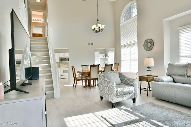 100 Turnberry Ct NE, Warren, OH 44484 - living area featuring stairs, a high ceiling, plenty of natural light, a chandelier, and light wood-style flooring
