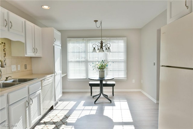 100 Turnberry Ct NE, Warren, OH 44484 - kitchen featuring freestanding refrigerator, a sink, a chandelier, dishwashing machine, and decorative backsplash