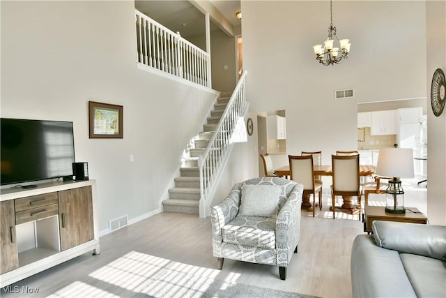 100 Turnberry Ct NE, Warren, OH 44484 - living room with a towering ceiling, stairway, a chandelier, light wood-style flooring, and baseboards