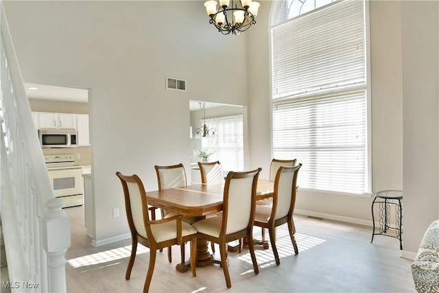 100 Turnberry Ct NE, Warren, OH 44484 - dining space featuring a chandelier, light wood-type flooring, baseboards, and a high ceiling