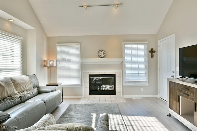 100 Turnberry Ct NE, Warren, OH 44484 - living room with vaulted ceiling, light wood-style flooring, baseboards, a tile fireplace, and track lighting