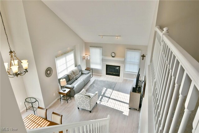 100 Turnberry Ct NE, Warren, OH 44484 - living area with wood finished floors, a glass covered fireplace, a chandelier, baseboards, and vaulted ceiling