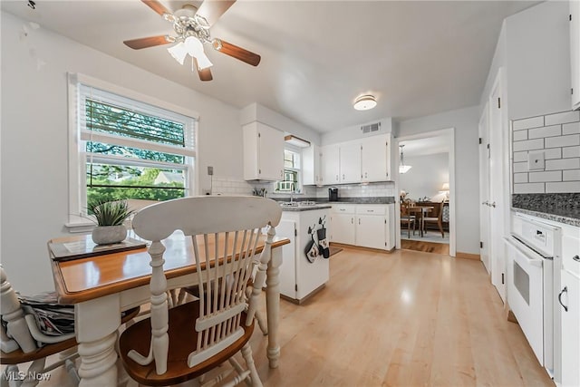 23903 E Baintree Rd, Beachwood, OH 44122 - kitchen with tasteful backsplash, white cabinets, a ceiling fan, dark countertops, and light wood-type flooring