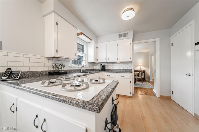 23903 E Baintree Rd, Beachwood, OH 44122 - kitchen with a peninsula, white gas cooktop, white cabinets, light wood finished floors, and backsplash
