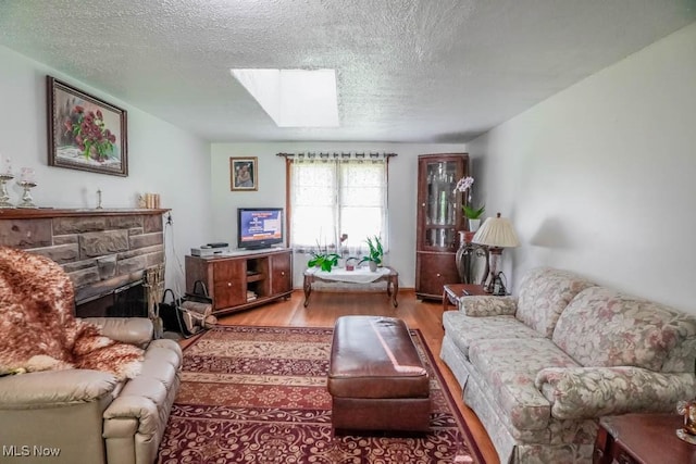 5920 Renninger Rd, New Franklin, OH 44319 - living room with a skylight, wood finished floors, a textured ceiling, and a stone fireplace