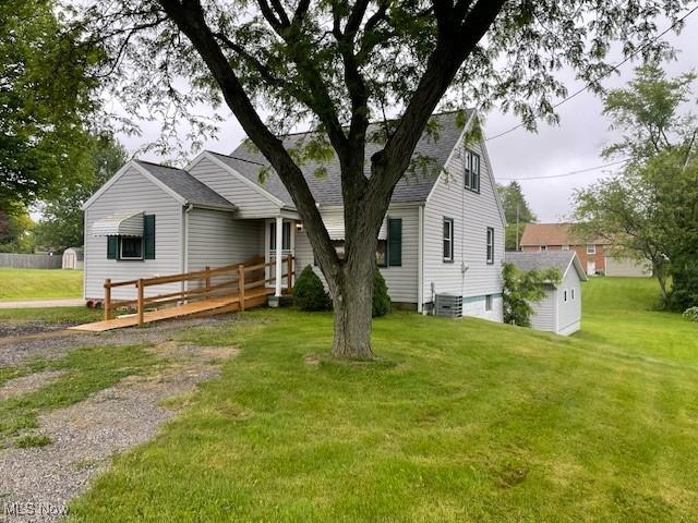 2410 Perry Dr SW, Canton, OH 44706 - view of front of house with a front lawn, an outbuilding, roof with shingles, and central AC unit