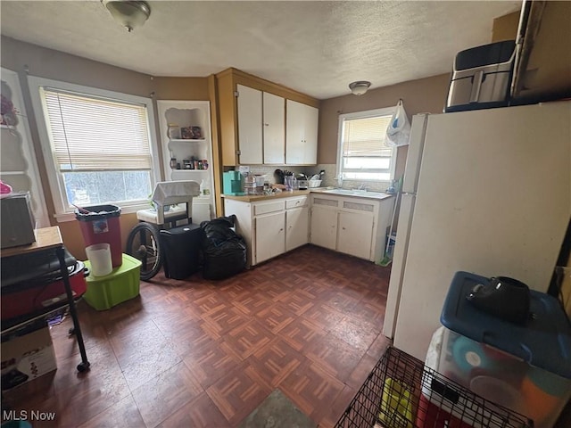 4154 E 153rd St, Cleveland, OH 44128 - kitchen featuring light countertops, a textured ceiling, freestanding refrigerator, white cabinets, and a sink