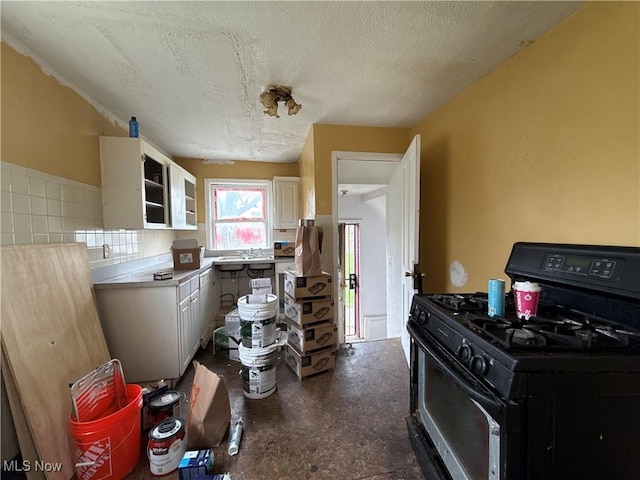 3833 E 144th St, Cleveland, OH 44128 - kitchen with black gas range oven, a textured ceiling, white cabinetry, light countertops, and a sink