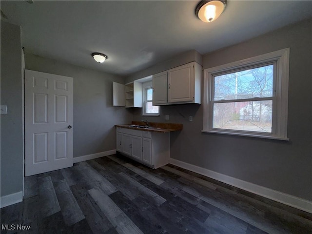 3877 E 153rd St, Cleveland, OH 44128 - kitchen with white cabinets, dark wood-style floors, a sink, baseboards, and healthy amount of natural light
