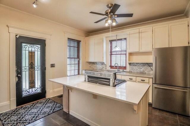 490 N Main St, Magnolia, OH 44643 - kitchen with freestanding refrigerator, a sink, ornamental molding, dark tile patterned flooring, and backsplash