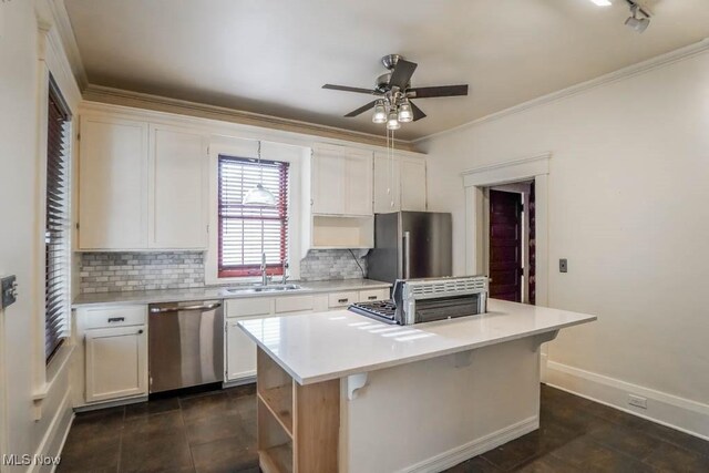 490 N Main St, Magnolia, OH 44643 - kitchen featuring stainless steel appliances, tasteful backsplash, ceiling fan, a center island, and ornamental molding
